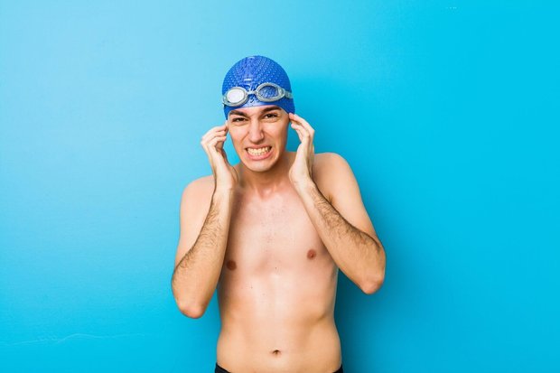 Young swimmer man covering ears with hands. Von Asier - Adobe Photo Stock