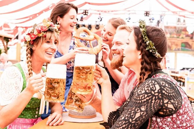 Gruppe von Freunden am Biertisch stoßen mit Maß an und lachen und flirten auf dem Oktoberfest. Von drubig-photo - Adobe Photo Stock
