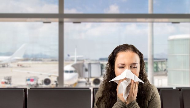 Sick woman sneezing at the airport. Von cunaplus - Adobe Photo Stock